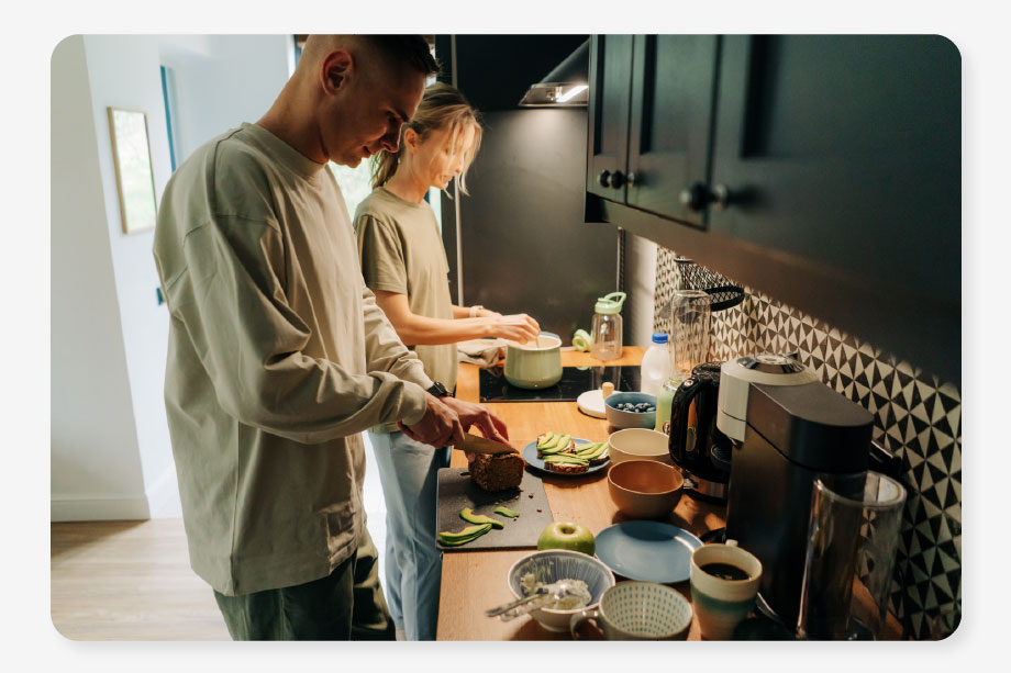 a couple stands in their kitchen cooking dinner surrounded by lights because they don't need to worry about high energy bills