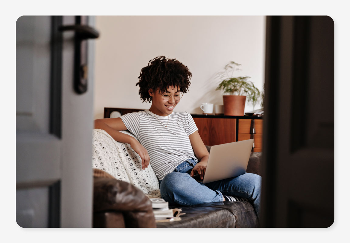 A woman sitting on her sofa using her superfast broadband deal from One Utility Bill