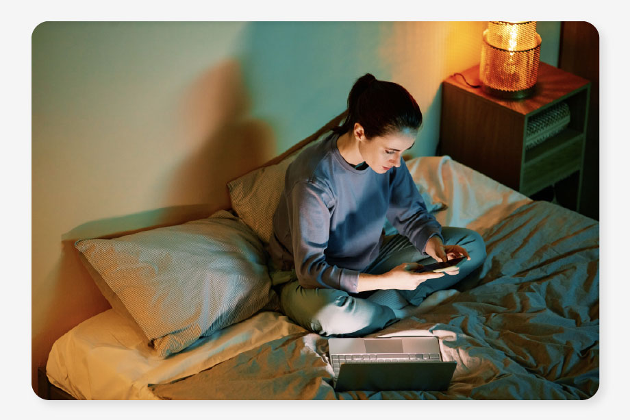 a woman sits in bed surrounded by cosy lights thanks to her unlimited energy bills package