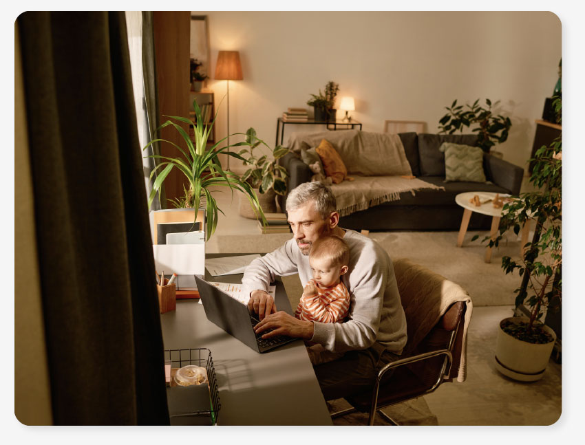 a man sits at a laptop with his baby on his lap figuring out easy energy bills 